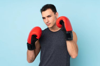 Mavi arka planda, boks eldivenleriyle izole edilmiş genç bir sporcu.