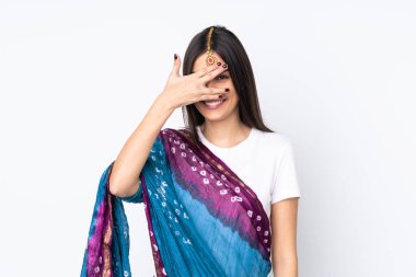 Beyaz arka planda izole edilmiş genç Hintli bir kadın. Gözleri elleriyle kaplıyor ve gülümsüyor.