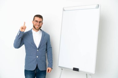 Beyaz arka planda izole edilmiş beyaz panoda sunum yapan genç iş kadını harika bir fikre işaret ediyor.