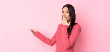 İzole edilmiş arka planda genç beyaz kadın sürpriz bir ifadeyle işaret ederken...