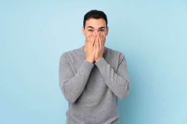 Mavi arka planda yalıtılmış beyaz, yakışıklı, şaşırtıcı bir yüz ifadesi olan genç adam.