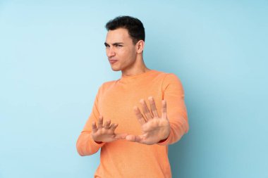 Beyaz tenli yakışıklı adam mavi arka planda izole edilmiş gergin eller öne uzanıyor.