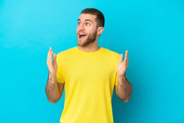 Mavi arka planda mahsur kalmış yakışıklı, beyaz bir adam. Şaşırtıcı bir yüz ifadesi var.