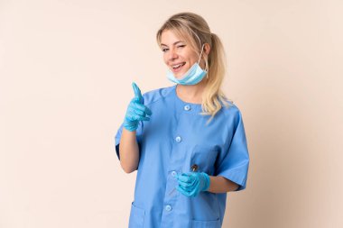 İzole edilmiş arka plan üzerinde aletleri tutan dişçi kadın seni işaret ediyor.