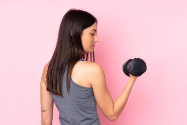 Pembe arka planda halter yapan genç bir kadın.