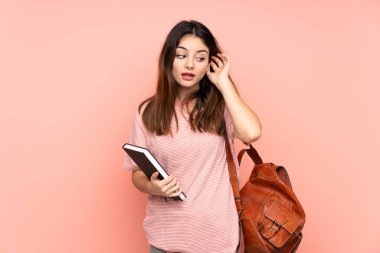 Üniversiteye giden genç bir bayan izole pembe arka planda bir şeyler dinliyor.