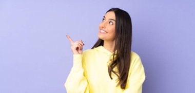 İzole edilmiş arka planda genç beyaz kadın harika bir fikre işaret ediyor.