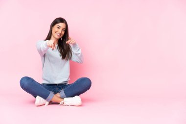 Pembe arka planda soyutlanmış beyaz bir kadın sana gülümserken parmak atıyor.