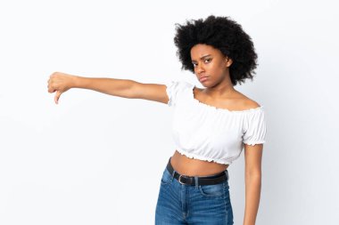 Beyaz arka planda izole edilmiş genç Afrikalı Amerikalı kadın, olumsuz ifadeyle baş parmağını aşağı gösteriyor.
