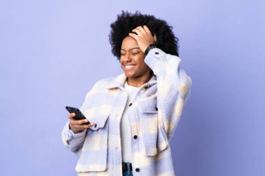 Mor arka planda izole edilmiş cep telefonu kullanan genç Afrikalı Amerikalı kadın bir şey fark etti ve çözümü arıyor.