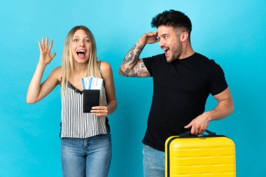 Genç beyaz çift mavi arka planda yalnız seyahat edecek. Şaşırmış ve şok olmuş bir yüz ifadesi var.