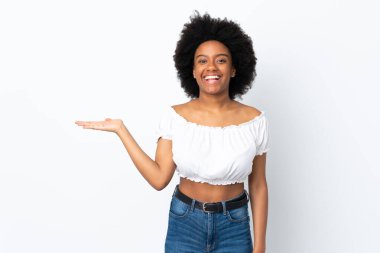 Beyaz arka planda izole edilmiş genç bir Afro-Amerikalı kadın bir ilan vermek için avucunun içinde hayali bir şey tutuyor.