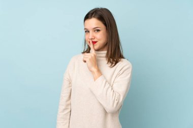 Mavi arka planda izole edilmiş genç kız sessizlik hareketi yapıyor.