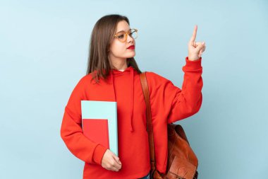 Mavi arkaplanda izole edilmiş kitapları tutan öğrenci kız şeffaf ekrana dokunuyor