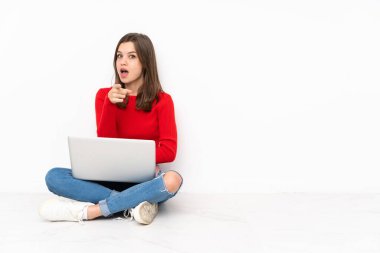 Polisle çalışan hassas kız beyaz arka planda izole edilmiş, şaşırmış ve ön tarafı işaret ediyor.