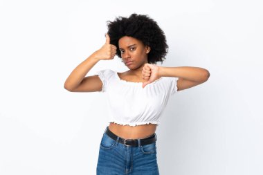 Beyaz arka planda izole edilmiş genç Afrikalı Amerikalı kadın iyiye-kötüye işaret yapıyor. Evet ya da hayır arasında kararsız