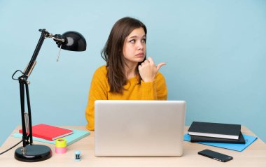 Öğrenci kız evinde çalışıyor. Mavi arka planda izole edilmiş. Mutsuz.