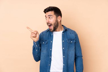Beyaz tenli yakışıklı adam bej arka planda izole edilmiş. Çözümü bulmak için parmağını kaldırıyor.