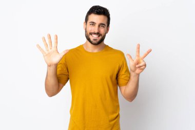 Beyaz arka planda sakallı yakışıklı genç adam sekiz parmaklı sayıyor.