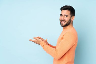 Kafkasyalı yakışıklı adam, izole edilmiş mavi arka planı alkışlıyor.