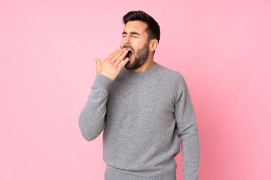 Kafkas yakışıklı adam izole edilmiş arka planda esniyor ve geniş ağzını eliyle kapatıyor.