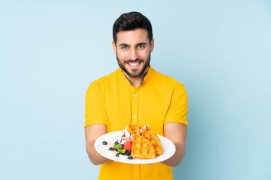 Beyaz adam mavi arka planda gözleme tutuyor.