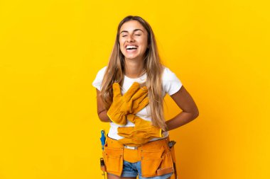 Genç İspanyol elektrikçi kadın izole edilmiş sarı duvarın üzerinde gülümsüyor.