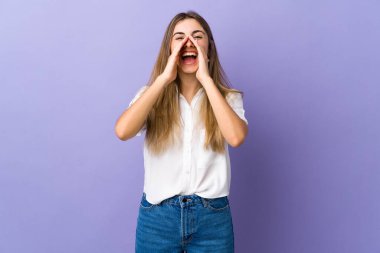 İzole edilmiş mor arka planda genç bir kadın bağırıyor ve bir şey duyuruyor.
