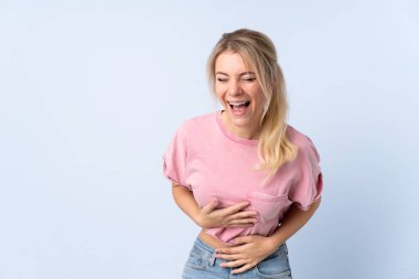 Sarışın kadın, izole edilmiş mavi arka planda gülümsüyor.