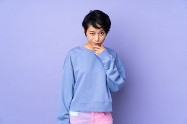 Genç Vietnamlı kadın, kısa saçlı, soyutlanmış mor arka planda.