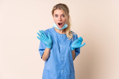 Diş hekimi kadının elinde, izole edilmiş bir arkaplanda şaşırtıcı bir yüz ifadesi var.