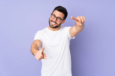 Kafkas yakışıklı adam izole edilmiş arka planda mutlu bir ifadeyle ön tarafı işaret ediyor.