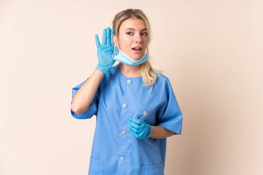 Dişçi kadın bir şeyler dinlerken izole edilmiş arka planda aletler tutuyor.