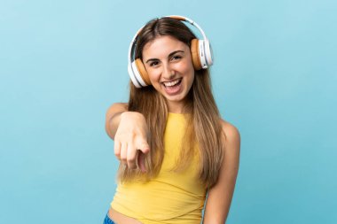 Soyutlanmış mavi arka planda müzik dinleyen genç bir kadın.