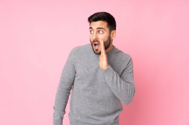 Kafkasyalı yakışıklı adam soyutlanmış arka planda. Yan tarafa bakarken sürpriz hareketlerle bir şeyler fısıldıyor.