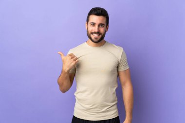 Tecrit edilmiş geçmişi olan sakallı yakışıklı genç bir adam bir ürün sunmak için kenarı işaret ediyor.