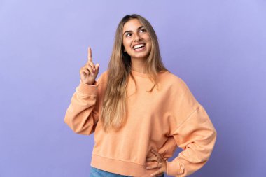 Tecrit edilmiş mor arka planı olan genç İspanyol kadın yukarı bakıyor ve şaşırıyor.