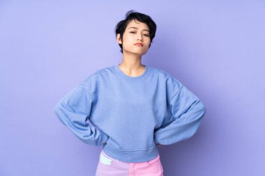 Kısa saçlı genç Vietnamlı kadın izole edilmiş mor arka planda kızgın.
