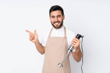 Beyaz arkaplanda izole edilmiş el blenderi kullanan adam parmağını yana doğru gösteriyor.