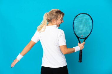 Genç Rus kadın mavi arka planda izole edilmiş tenis oynuyor ve zaferi kutluyor.