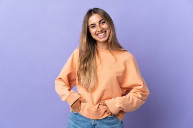 Soyutlanmış mor arka planda gülen genç İspanyol kadın.