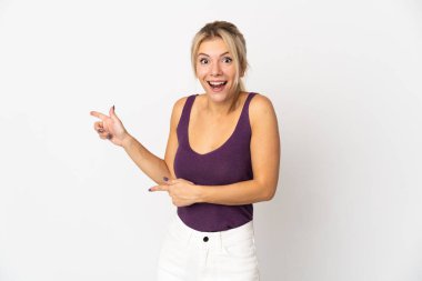 Beyaz arka planda izole edilmiş genç bir Rus kadın şaşırmış ve işaret ediyor.