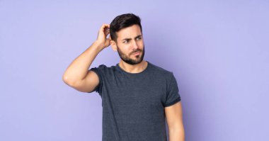 Kafkasyalı yakışıklı bir adamın, izole edilmiş mor arkaplanı tırmalarken şüpheleri var.