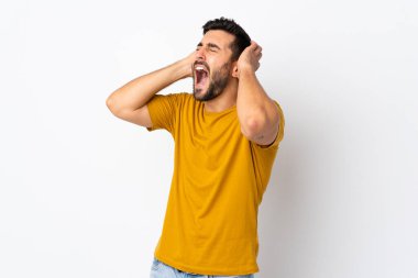 Beyaz arka planda sakallı yakışıklı bir genç bunalıma girmiş.