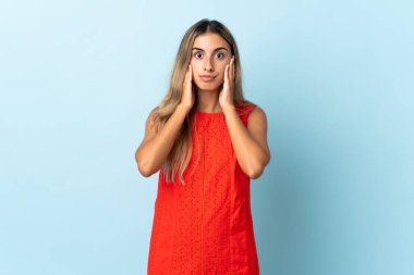 İzole edilmiş mavi arka planda genç İspanyol kadın hayal kırıklığına uğramış ve kulaklarını kapatmış.
