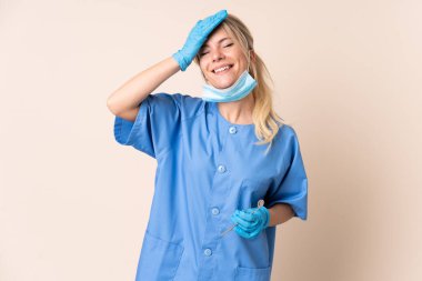 Dişçi kadın arka planda aletlerle gülüyor.