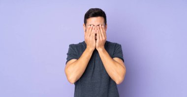 İzole edilmiş mor arka plan üzerinden gözlerini kapayan beyaz yakışıklı bir adam.