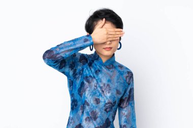 Genç Vietnamlı bir kadın, kısa saçlı, geleneksel bir elbise giyiyor, izole edilmiş beyaz bir arka plan, gözleri elle kaplıyor. Bir şey görmek istemiyorum.