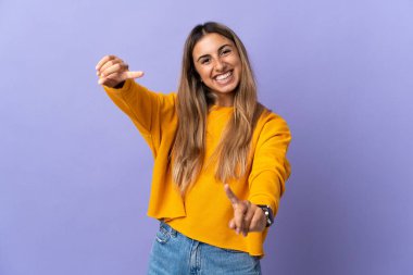 İzole edilmiş mor arka planda genç İspanyol kadın mutlu bir ifadeyle öne çıkıyor.