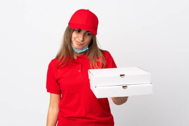 Pizza teslimatçısı kadın elinde pizza tutuyordu. Koronavirüsten koruyordu. İzole edilmiş beyaz bir maskeyle hüzünlü bir ifadeyle.